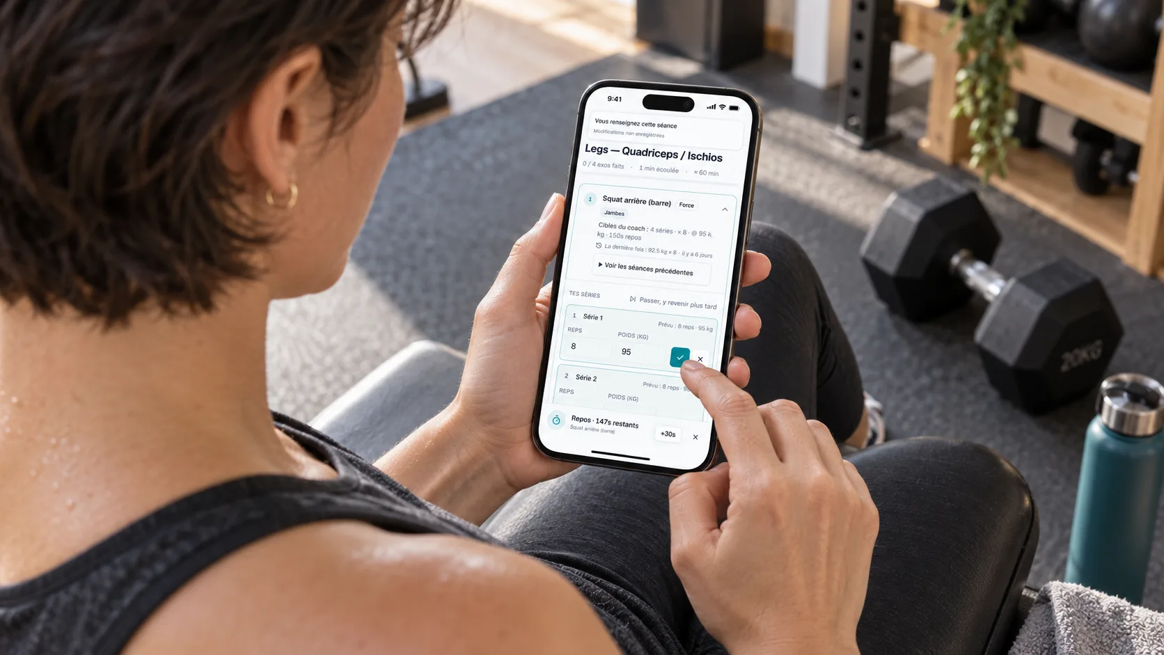 Élève sportive enregistrant une série terminée dans Adhérence sur son téléphone entre deux exercices.