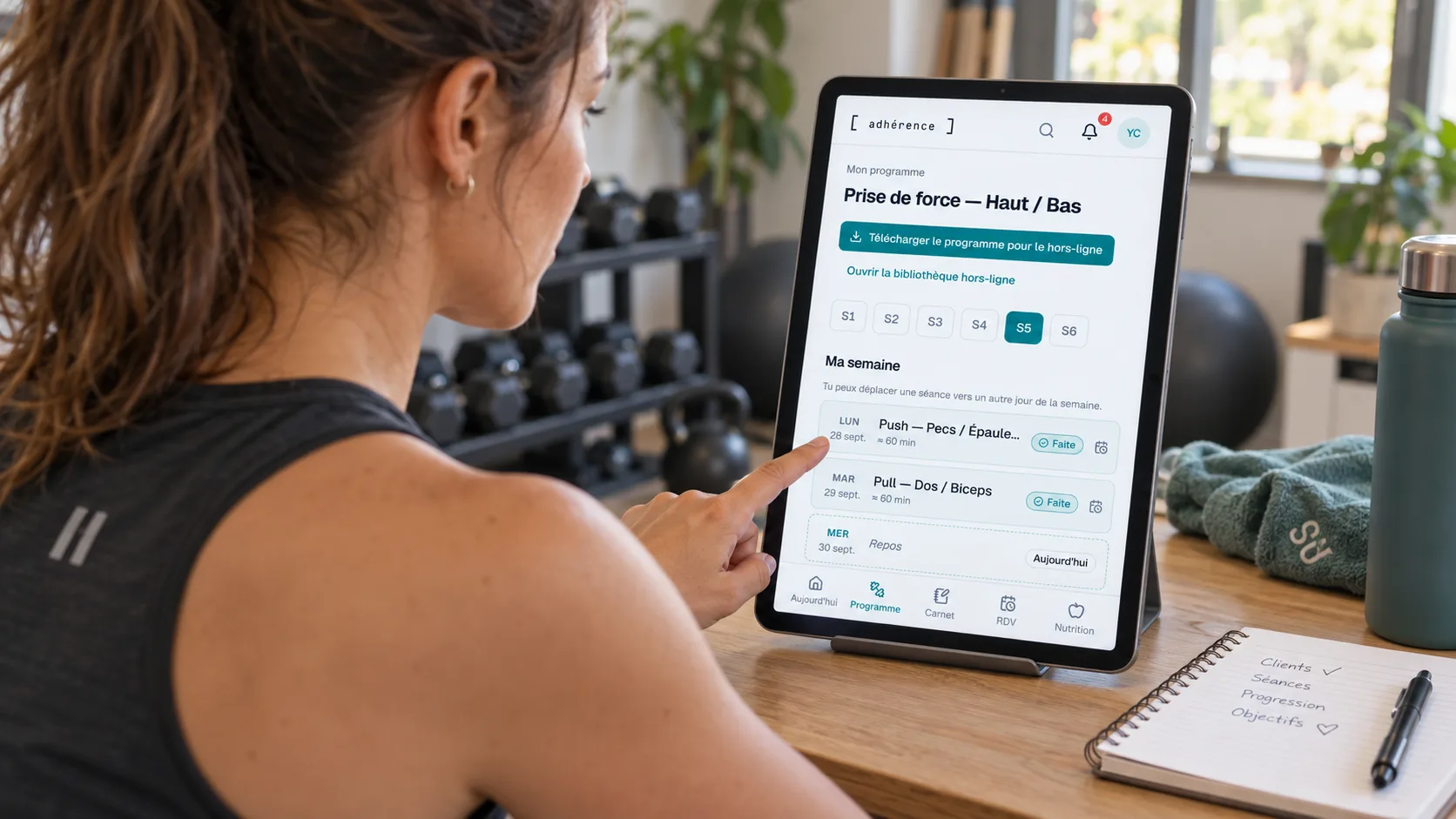 Coach sportive préparant le suivi de ses élèves dans Adhérence sur une tablette.