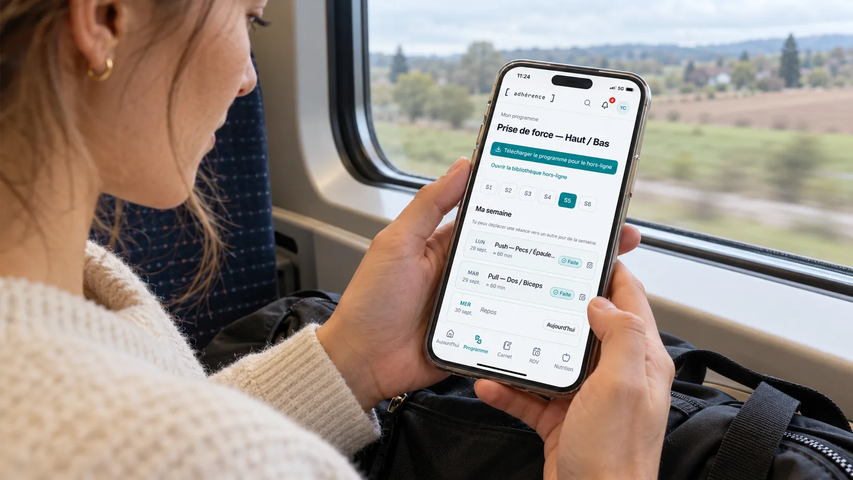 Coach préparant la prochaine période d’un programme Adhérence sur téléphone pendant un trajet en train.