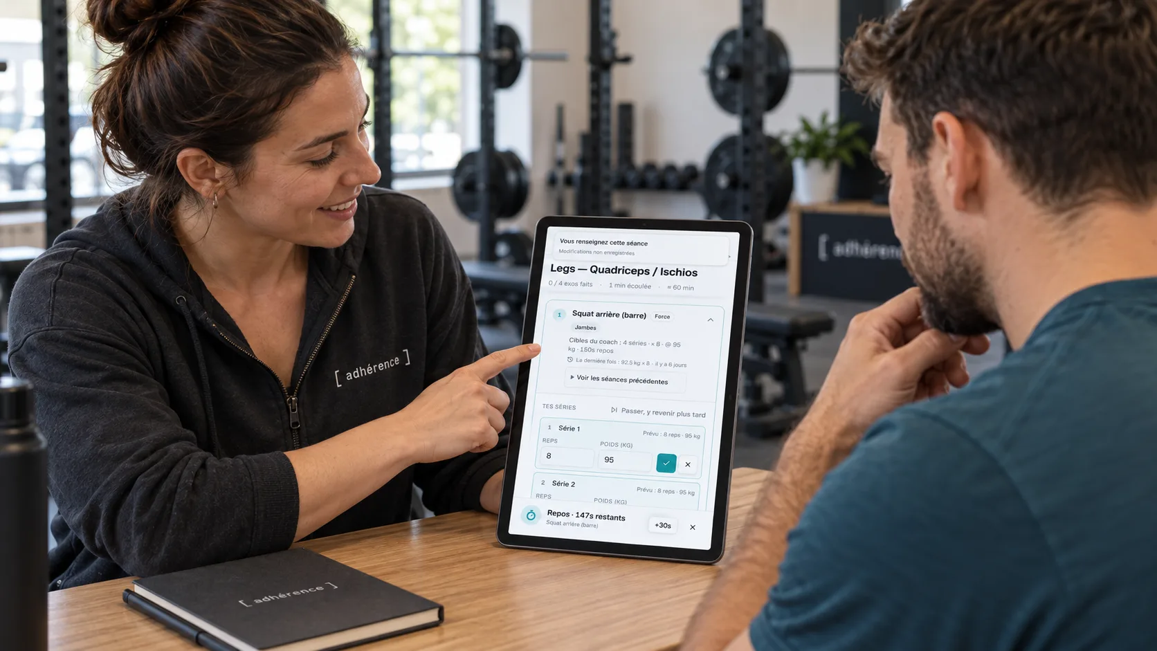 Coach et élève discutant de l’effort ressenti à partir du carnet de séance Adhérence sur une tablette.