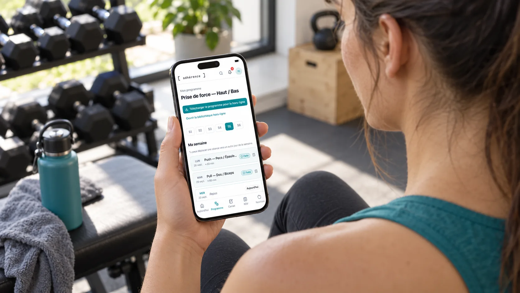 Élève consultant son programme Adhérence sur un téléphone après son entraînement.